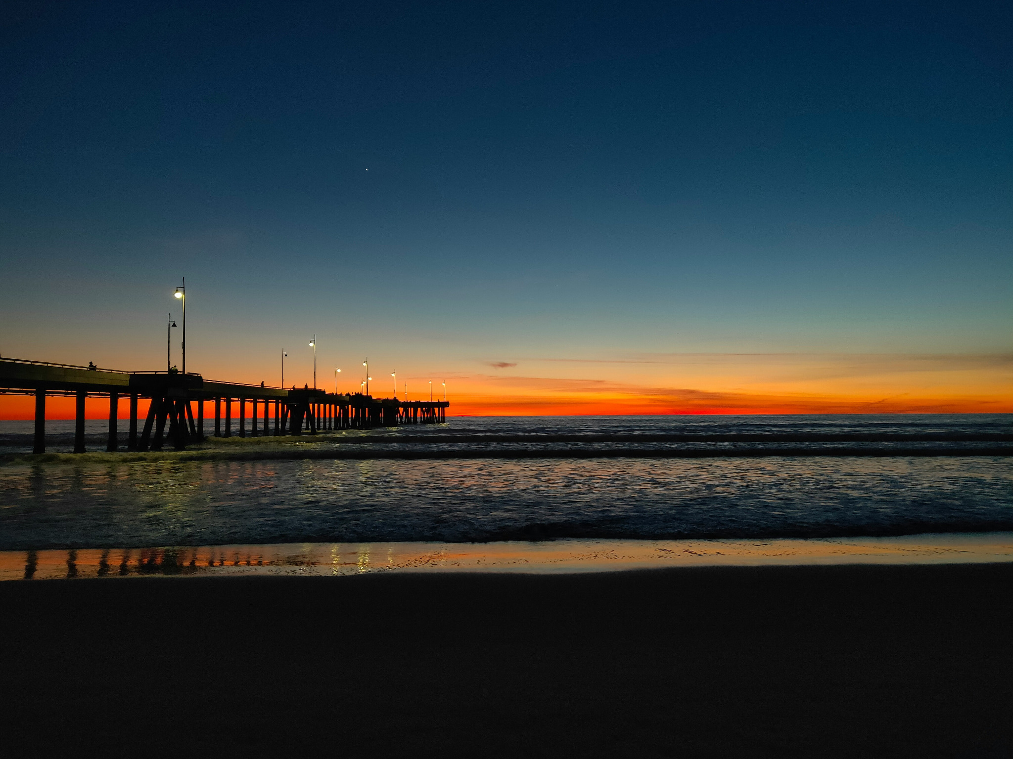 A pier extending into the Pacific Ocean at sunset